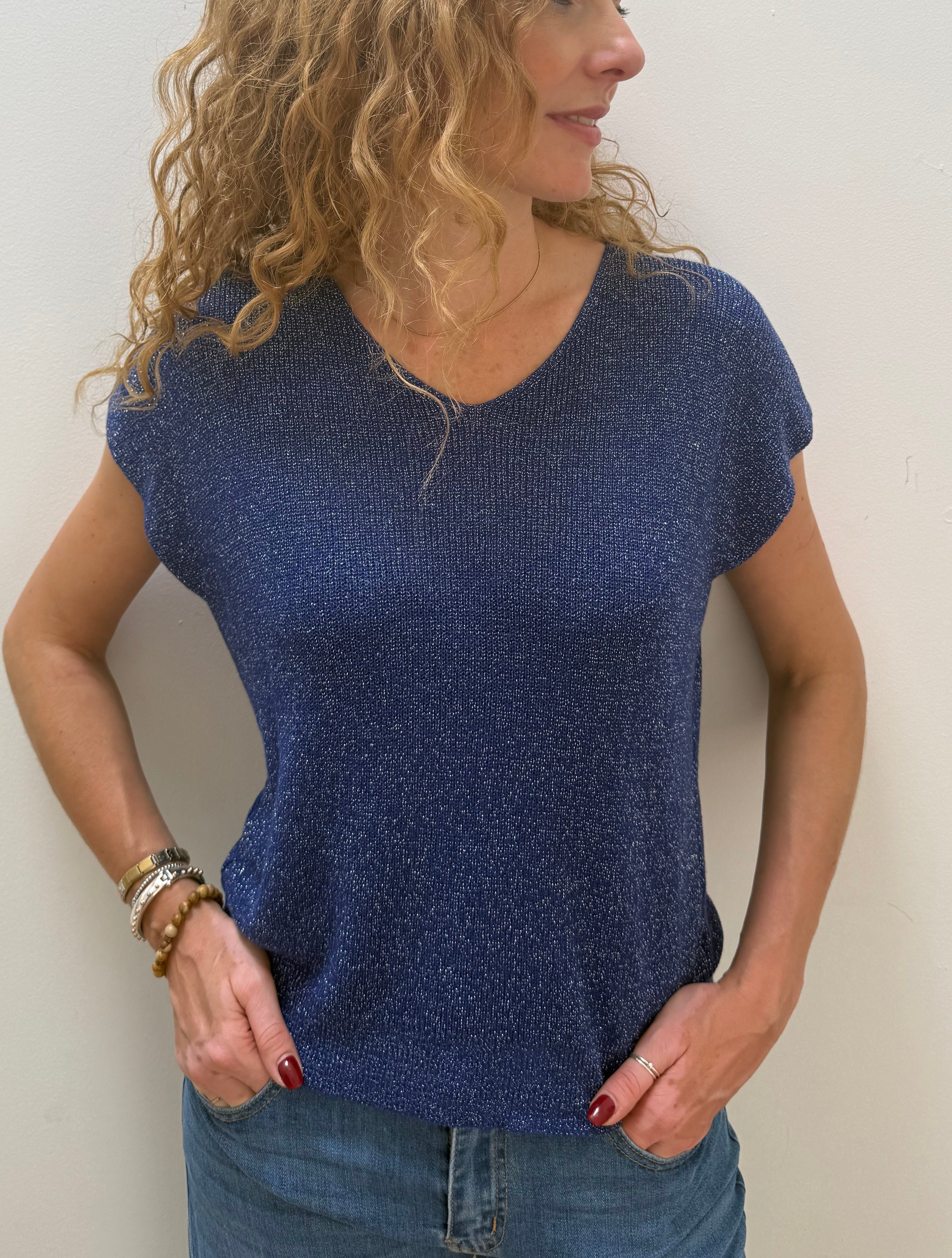 Woman wearing a blue top and jeans against a white background