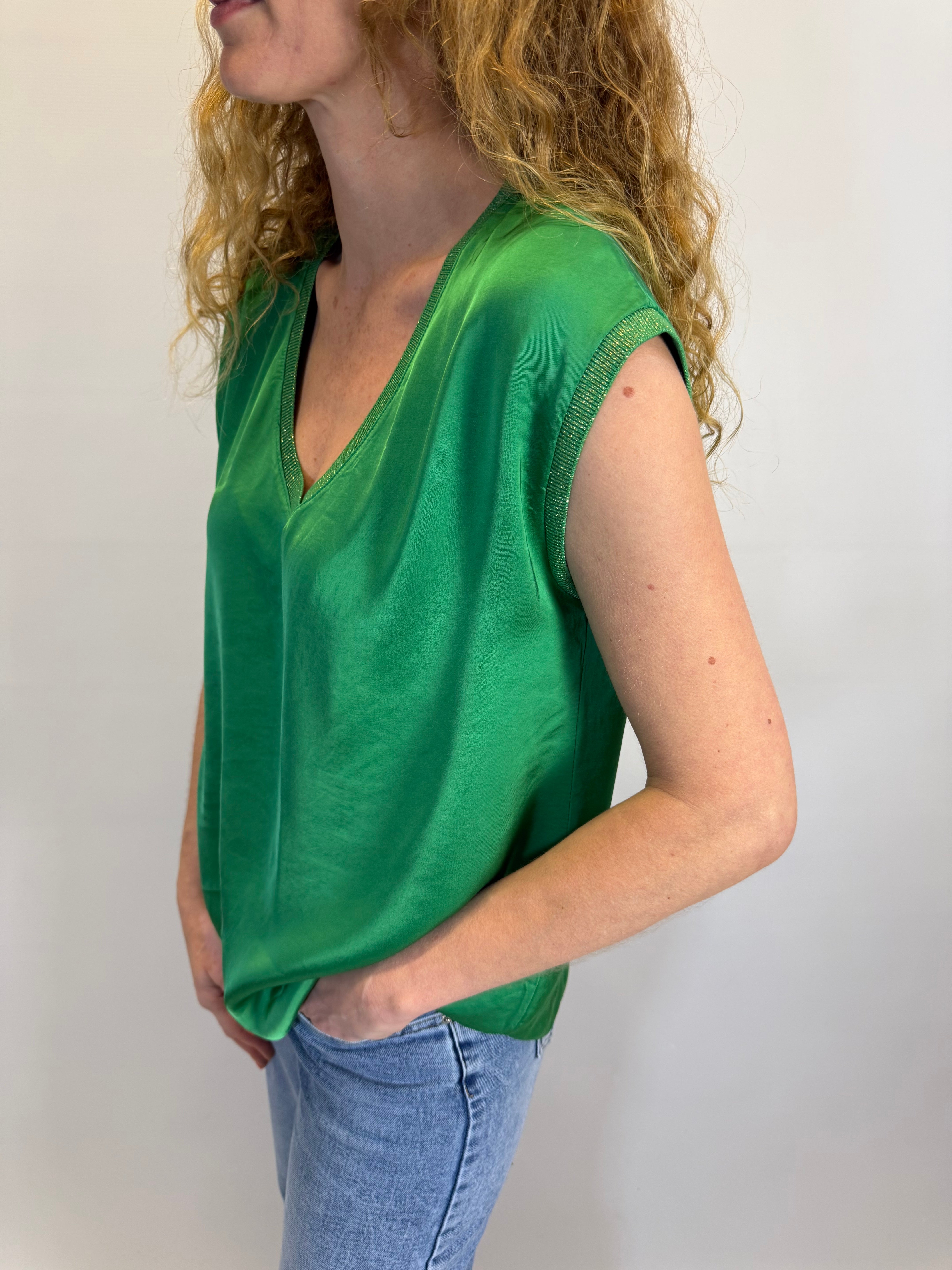 Person wearing a green top and blue jeans on a plain background