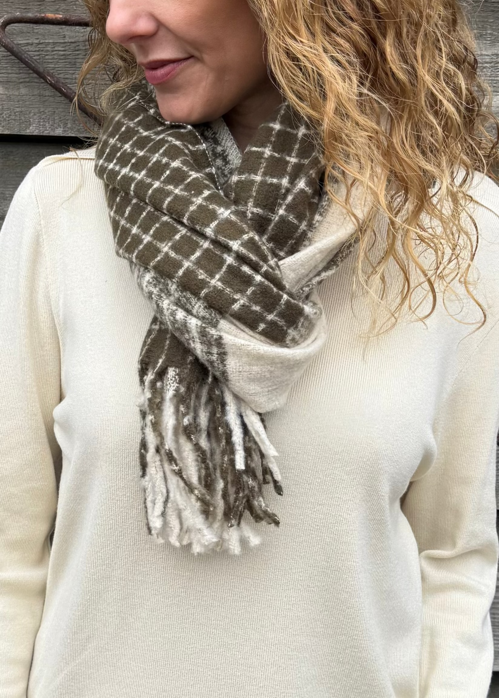 Woman wearing a plaid scarf against a wooden wall
