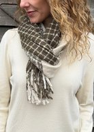 Woman wearing a plaid scarf against a wooden wall