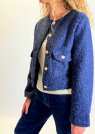 Person wearing a blue textured jacket with a plain background