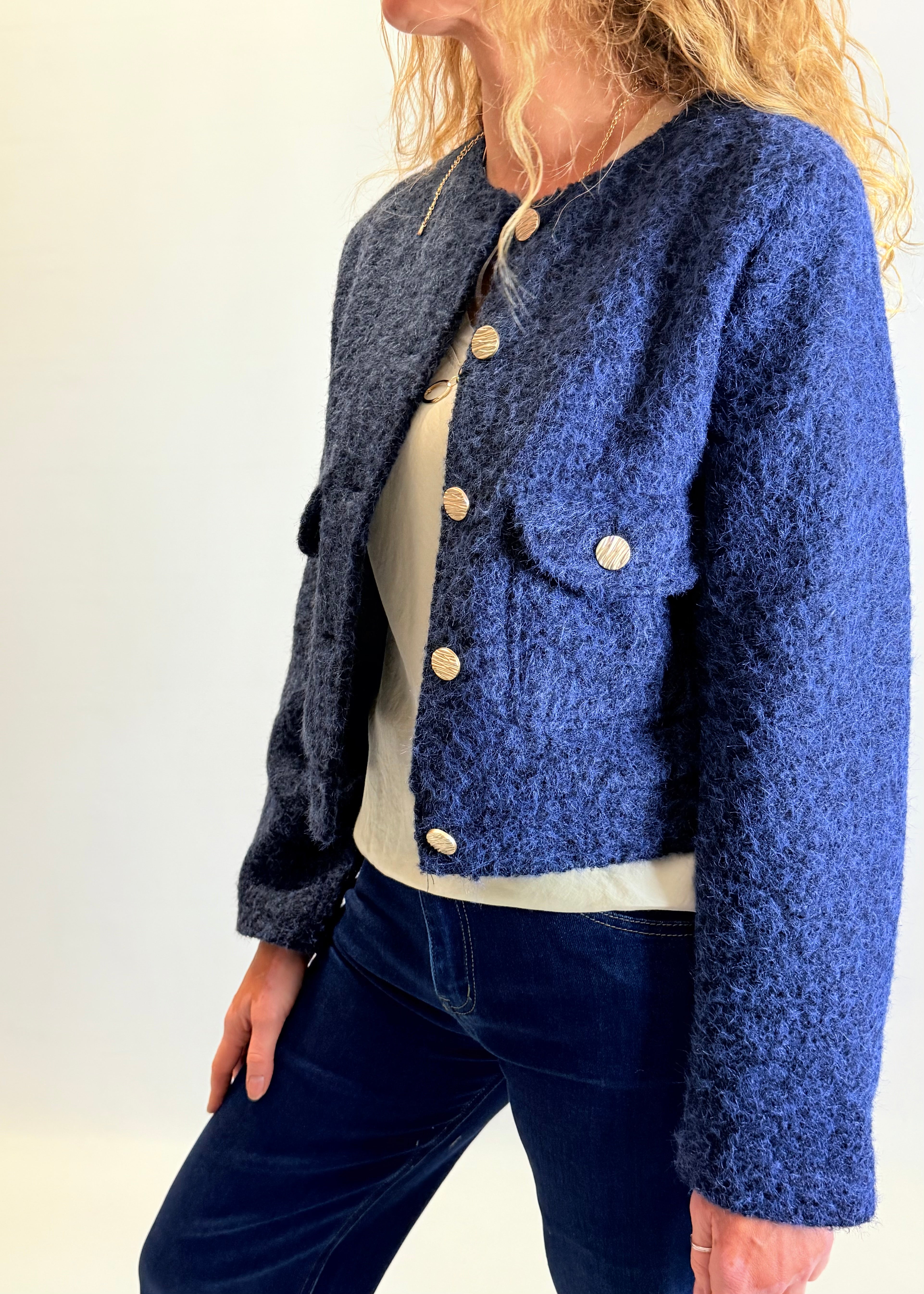 Person wearing a blue textured jacket with a plain background