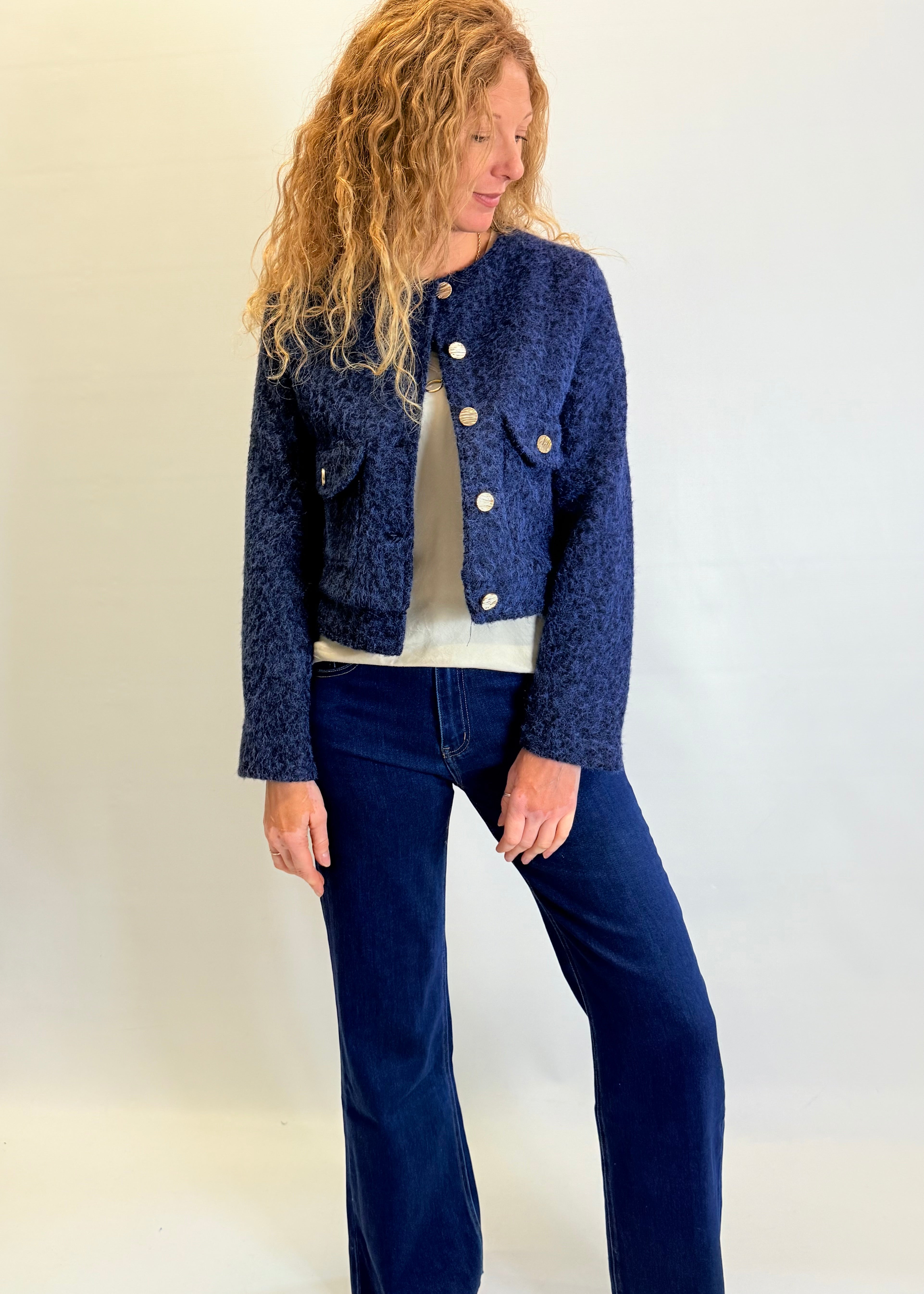 Woman wearing a blue textured jacket and jeans against a white background