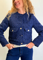 Woman wearing a blue textured jacket with a plain background