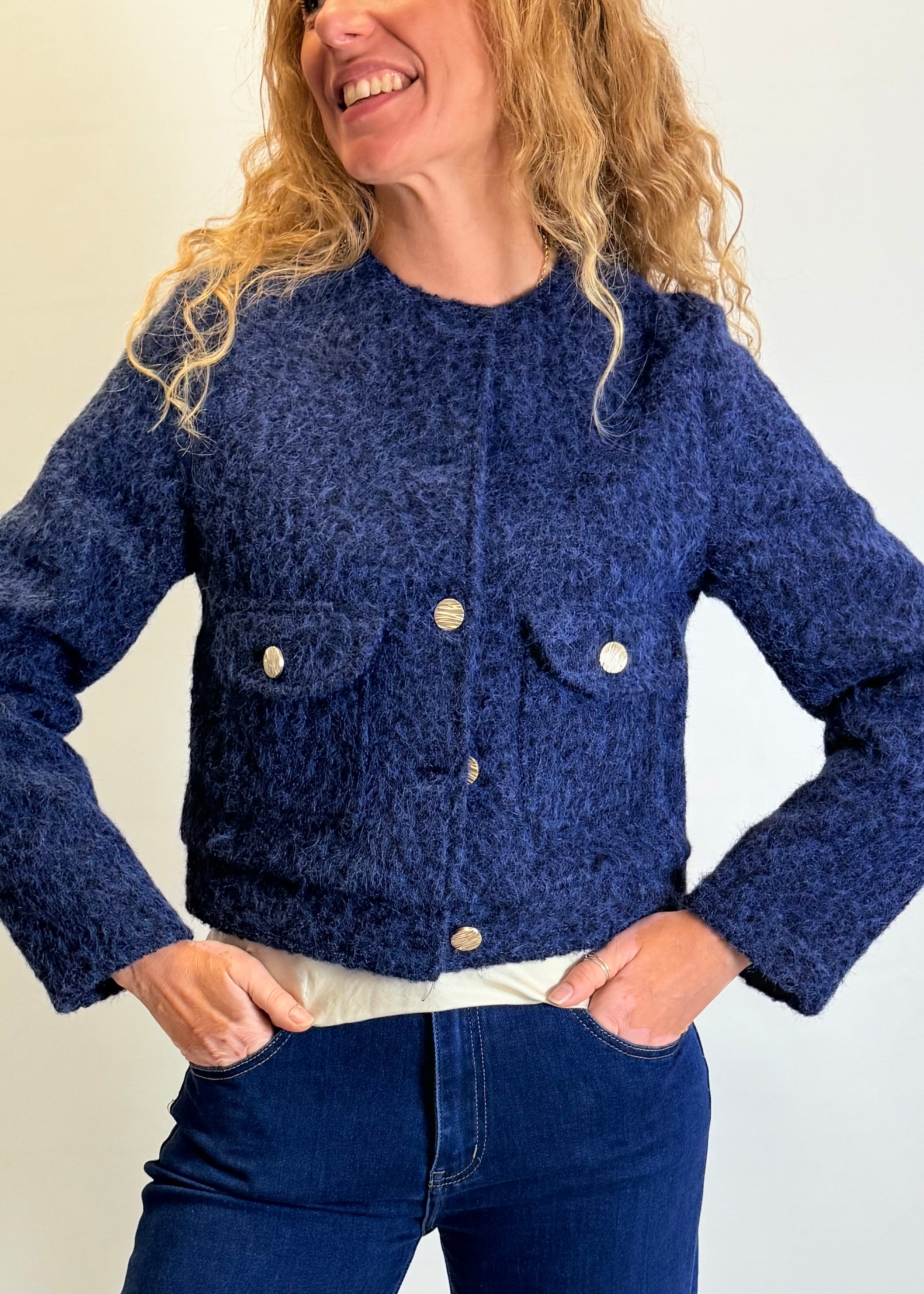 Woman wearing a blue textured jacket with a plain background