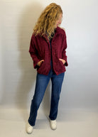Person wearing a red jacket and blue jeans against a plain background