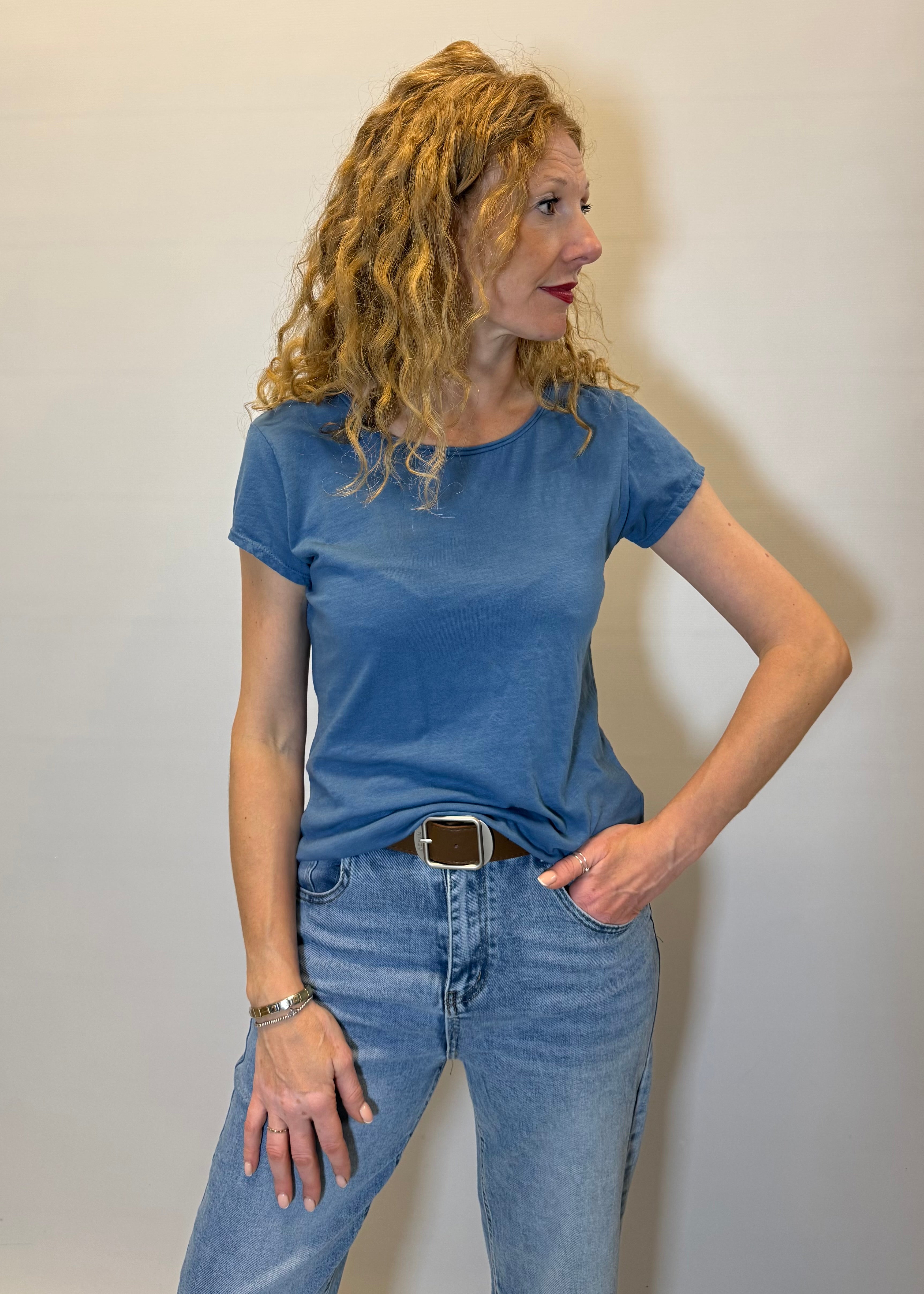 Woman wearing a blue t-shirt and jeans against a plain background