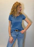 Woman wearing a blue t-shirt and jeans against a plain background