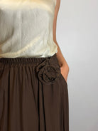 Brown skirt with a flower detail worn by a person against a white background