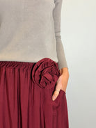 Maroon skirt with a floral detail worn by a person against a plain background