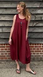 Woman in a burgundy dress standing against a wooden wall.