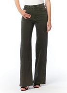 A model wearing a pair of dark olive green wide-leg jeans with a white top and black sandals, shown from the waist down against a white studio background.