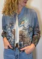 Woman wearing a floral-patterned bomber jacket against a plain background