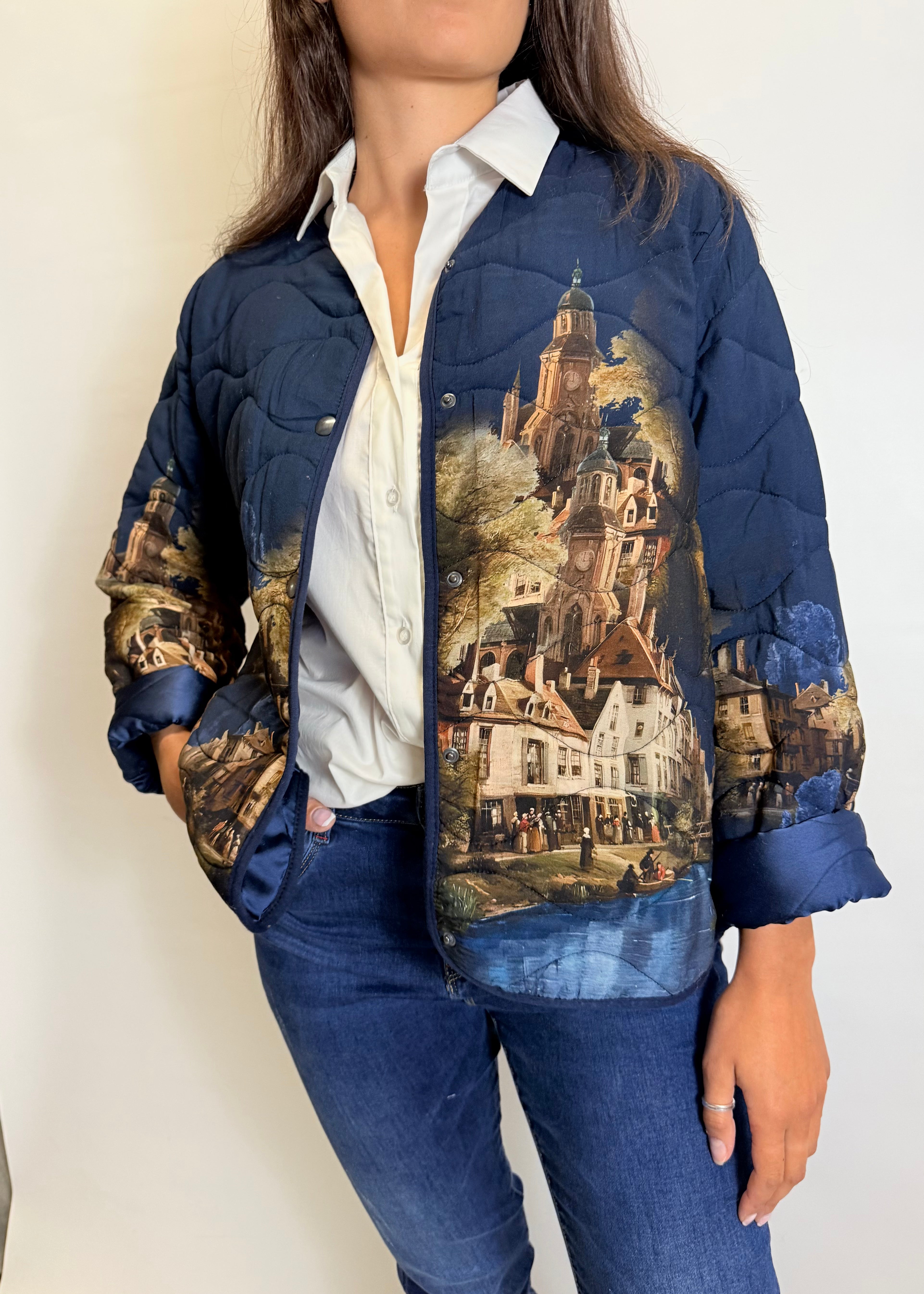 Person wearing a blue quilted jacket with a scenic print on a plain background