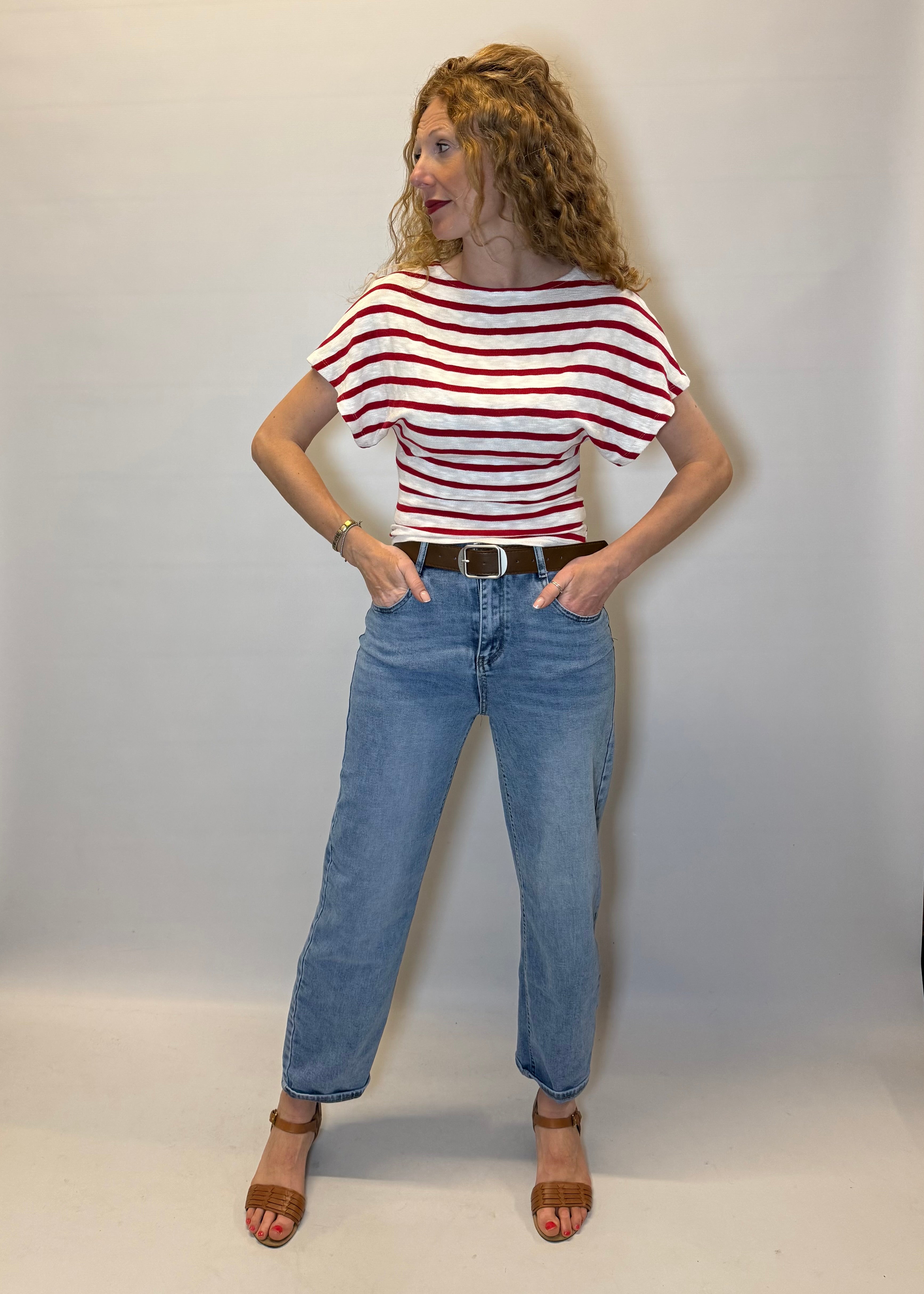 Person wearing a red and white striped shirt and blue jeans against a plain background