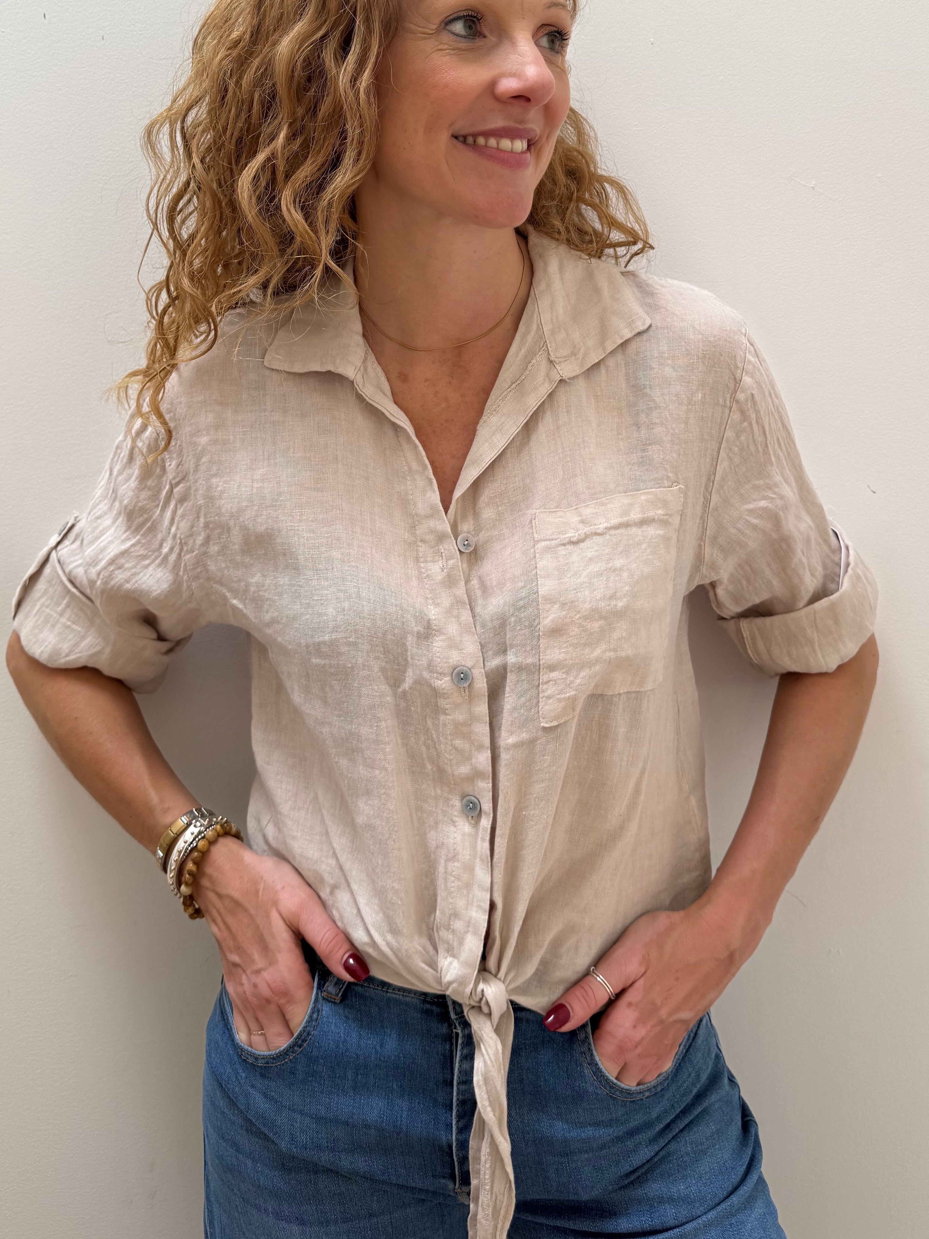 Woman wearing a beige blouse and blue jeans against a white background