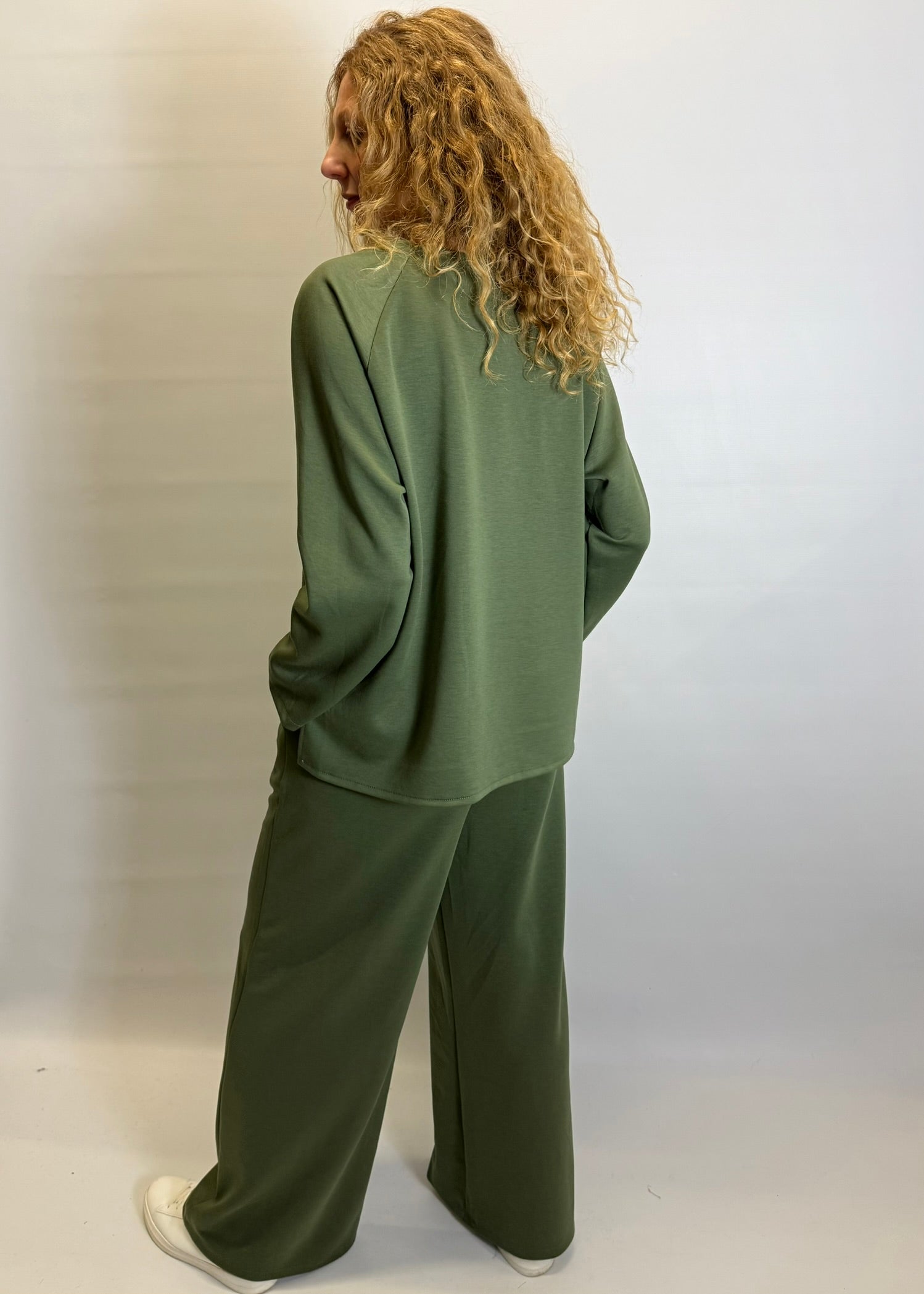 Person wearing a green tracksuit against a plain background