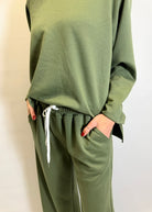 Green sweatshirt and pants set on a plain background