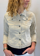 Person wearing a light-colored denim jacket against a plain background