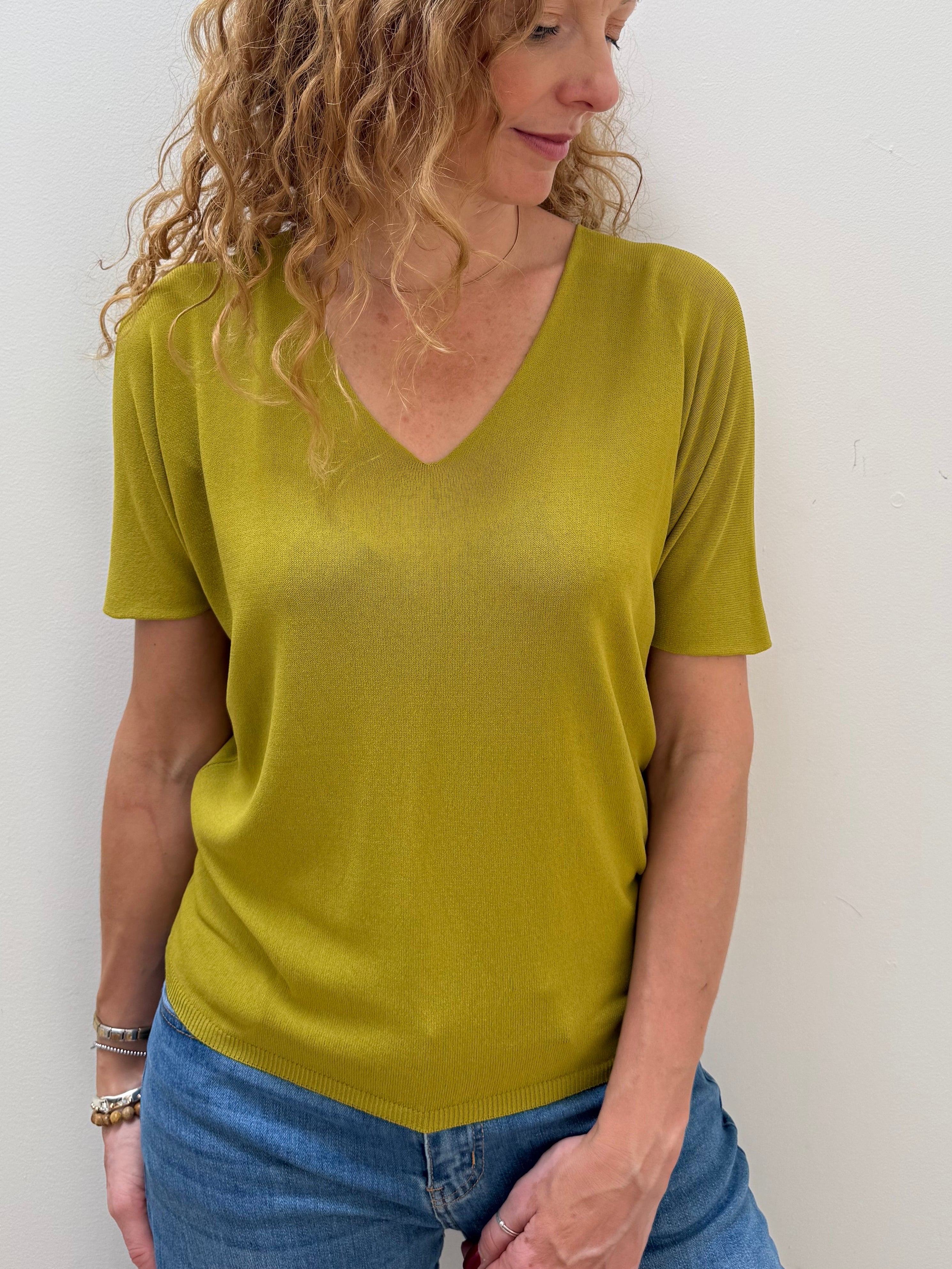 Woman wearing a green shirt and blue jeans against a white background