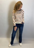 Woman wearing a striped sweater and jeans against a plain background