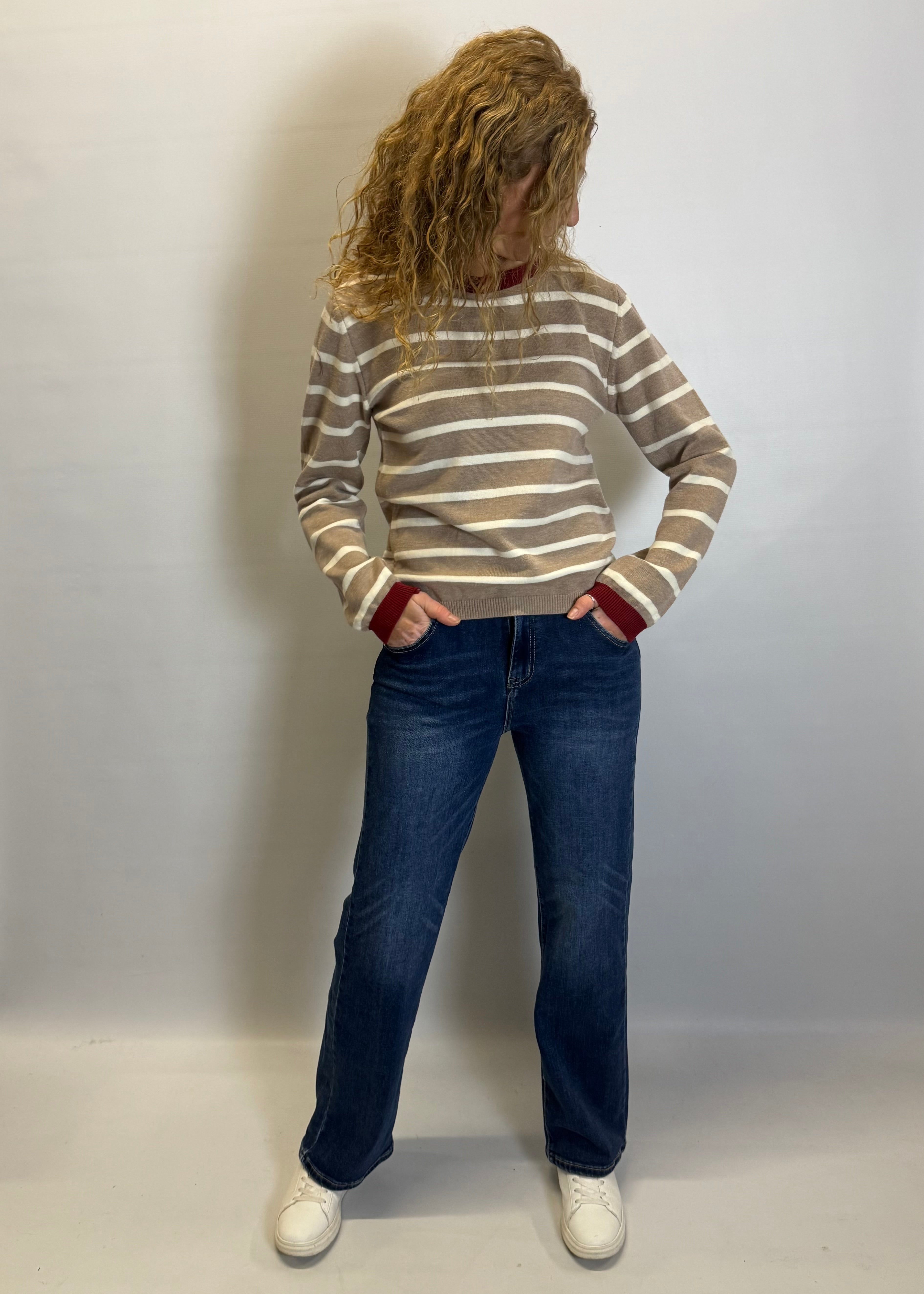 Person wearing a striped sweater and jeans against a plain background