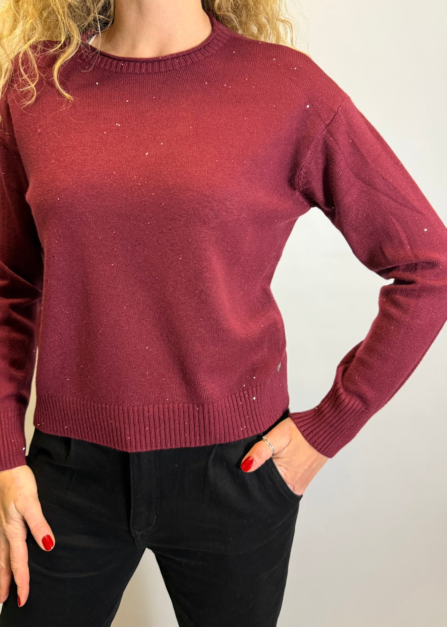 Maroon sweater worn by a person on a plain background