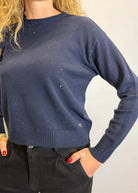 Navy blue sweater worn by a person on a plain background