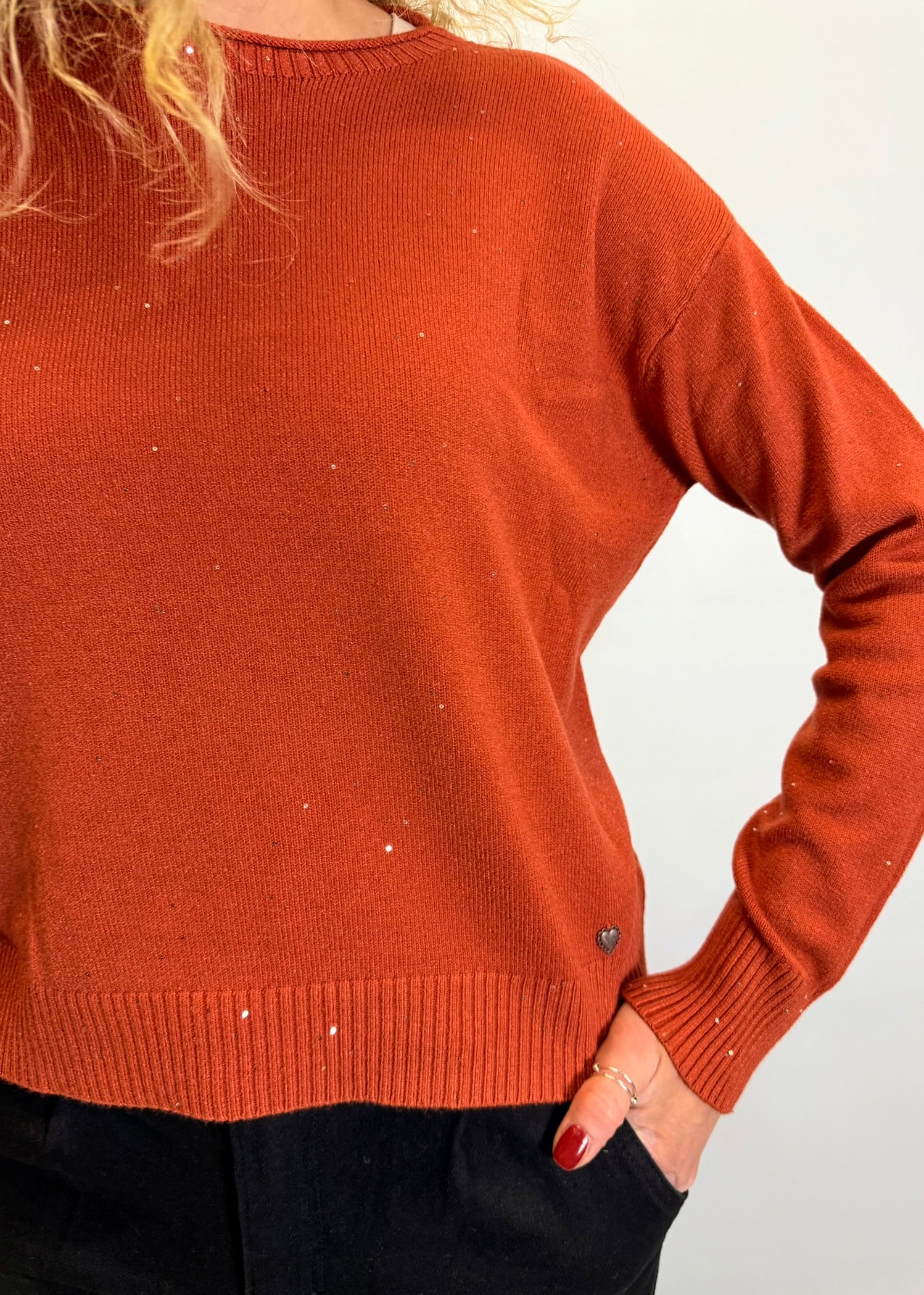 Person wearing a rust-colored sweater against a white background