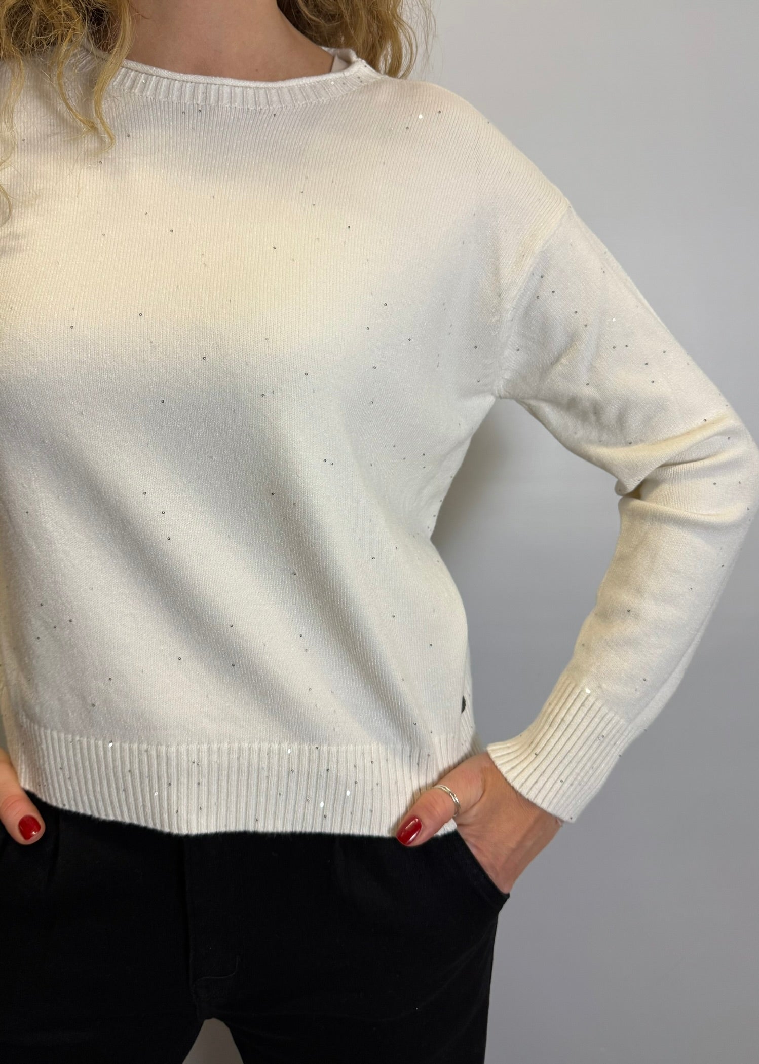 White sweater worn by a person with a plain background