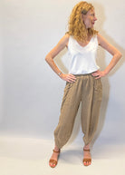 Woman wearing a white top and beige pants against a plain background