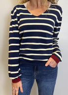Person wearing a navy and white striped sweater with red cuffs and hem, paired with blue jeans.