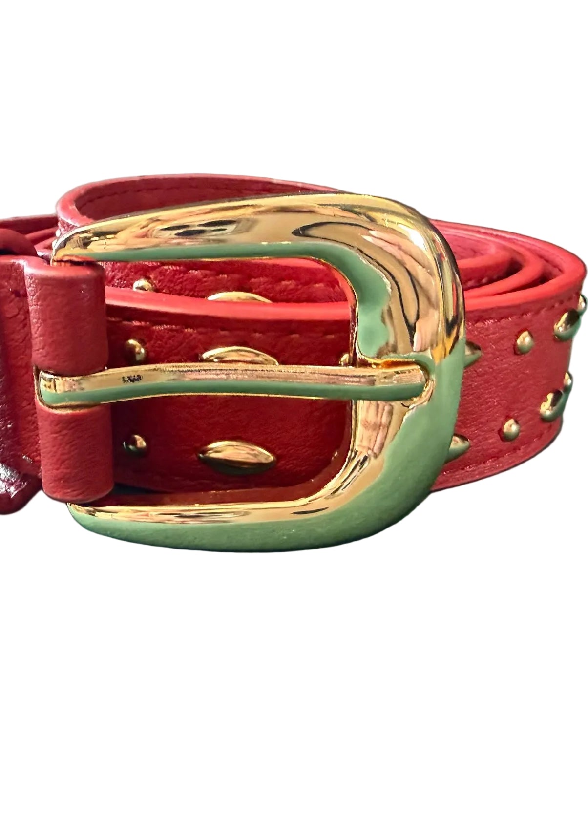 Red leather belt with gold buckle on a green surface