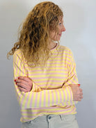 Person wearing a yellow and pink striped shirt against a plain background