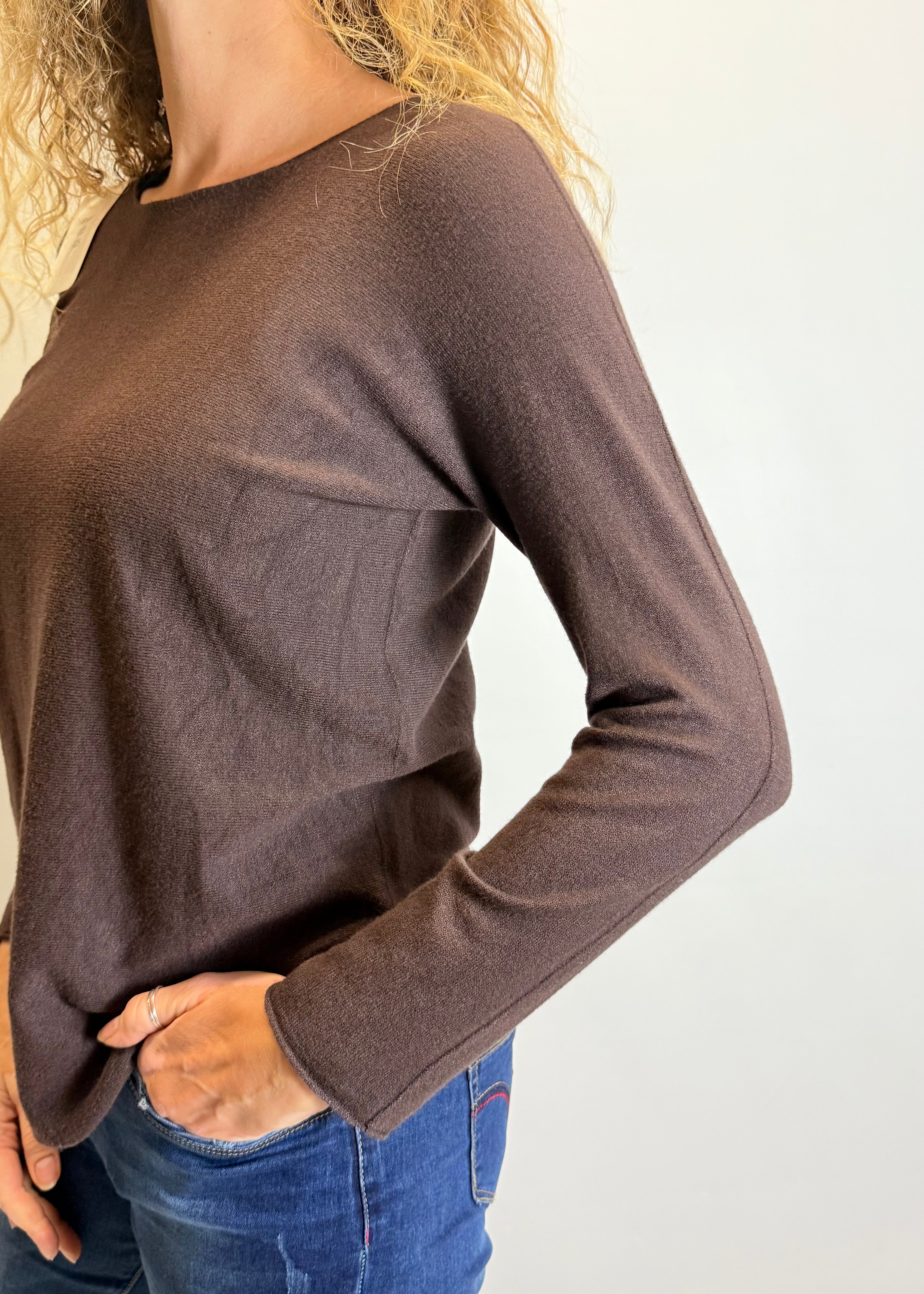 Person wearing a brown long-sleeve top with a blurred background