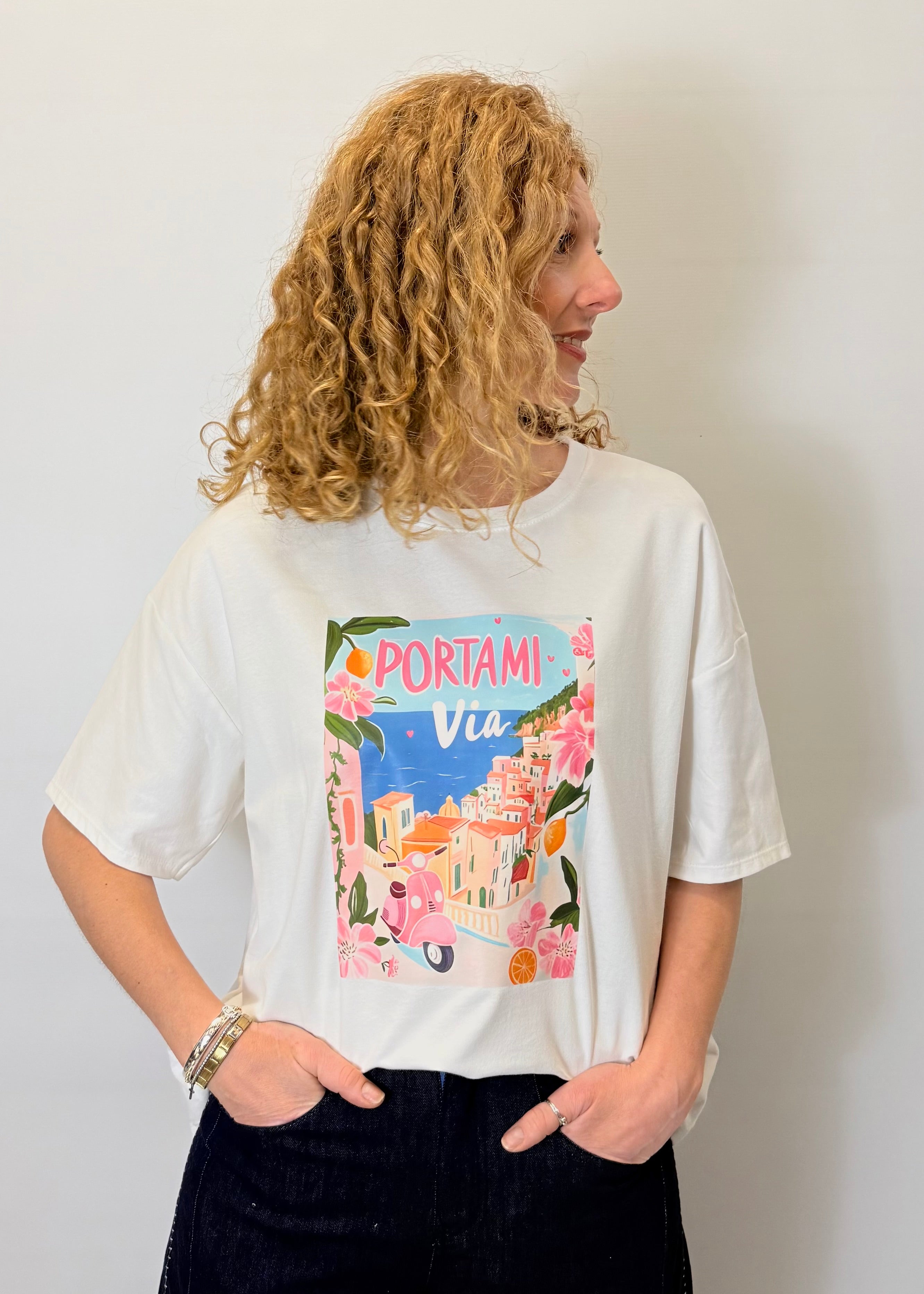 Person wearing a white t-shirt with a colorful graphic design on a plain background