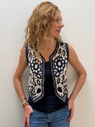 Woman wearing a sleeveless patterned top against a plain background