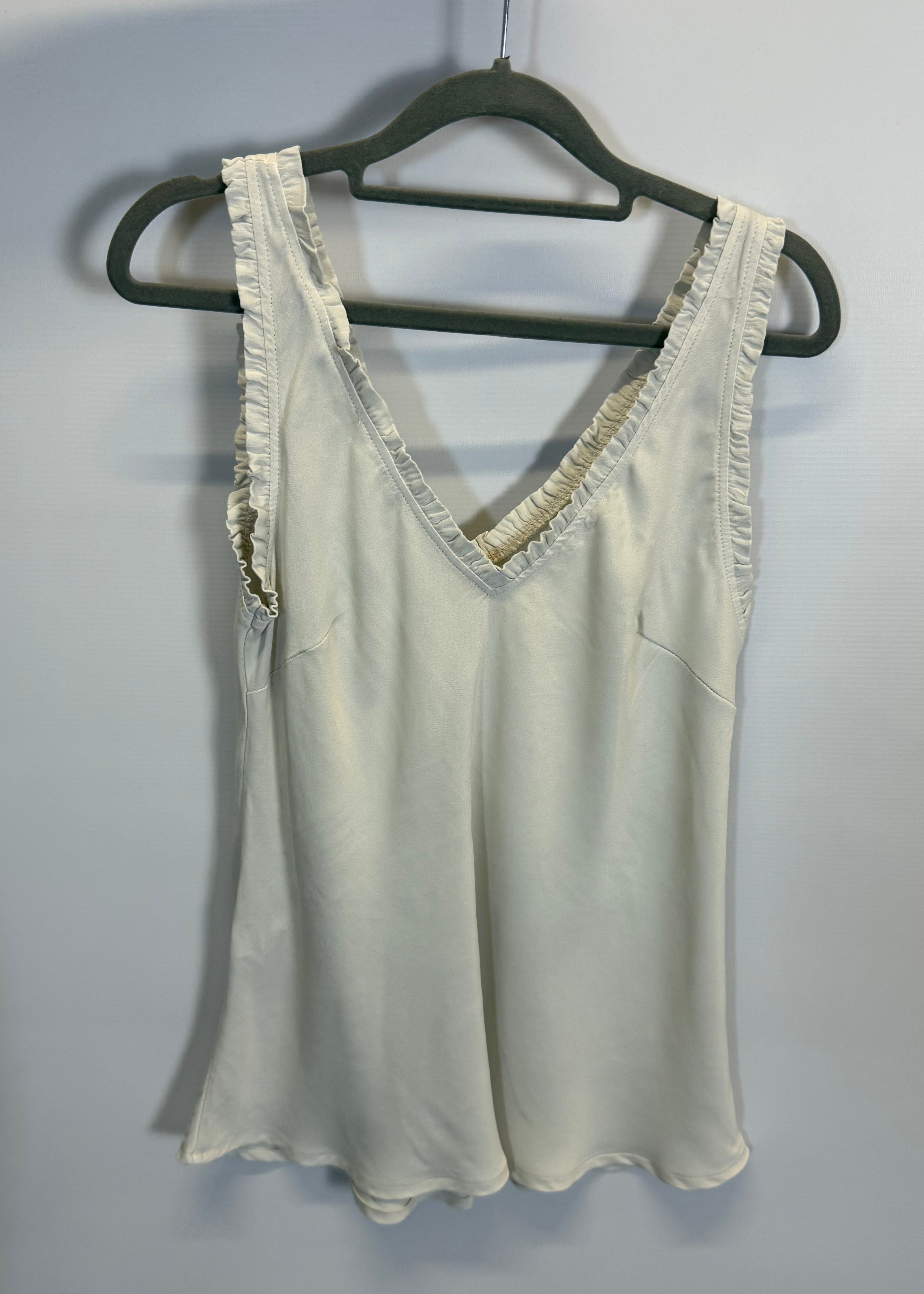 White top with lace trim on a hanger against a plain background