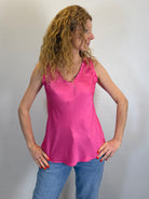 Woman wearing a pink sleeveless top and blue jeans against a plain background
