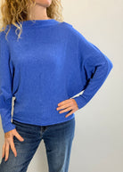 Person wearing a blue sweater and jeans against a plain background