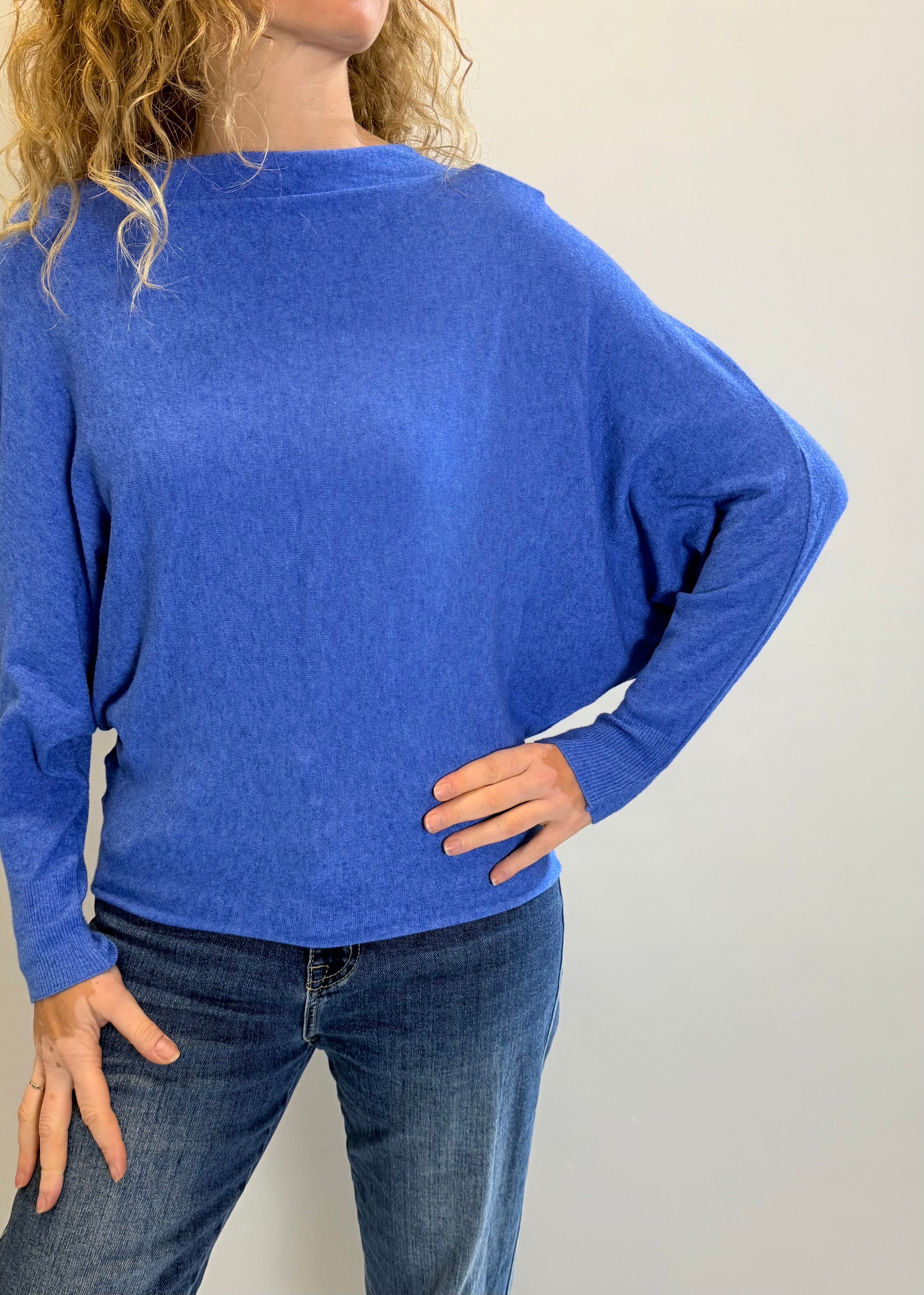 Person wearing a blue sweater and jeans against a plain background