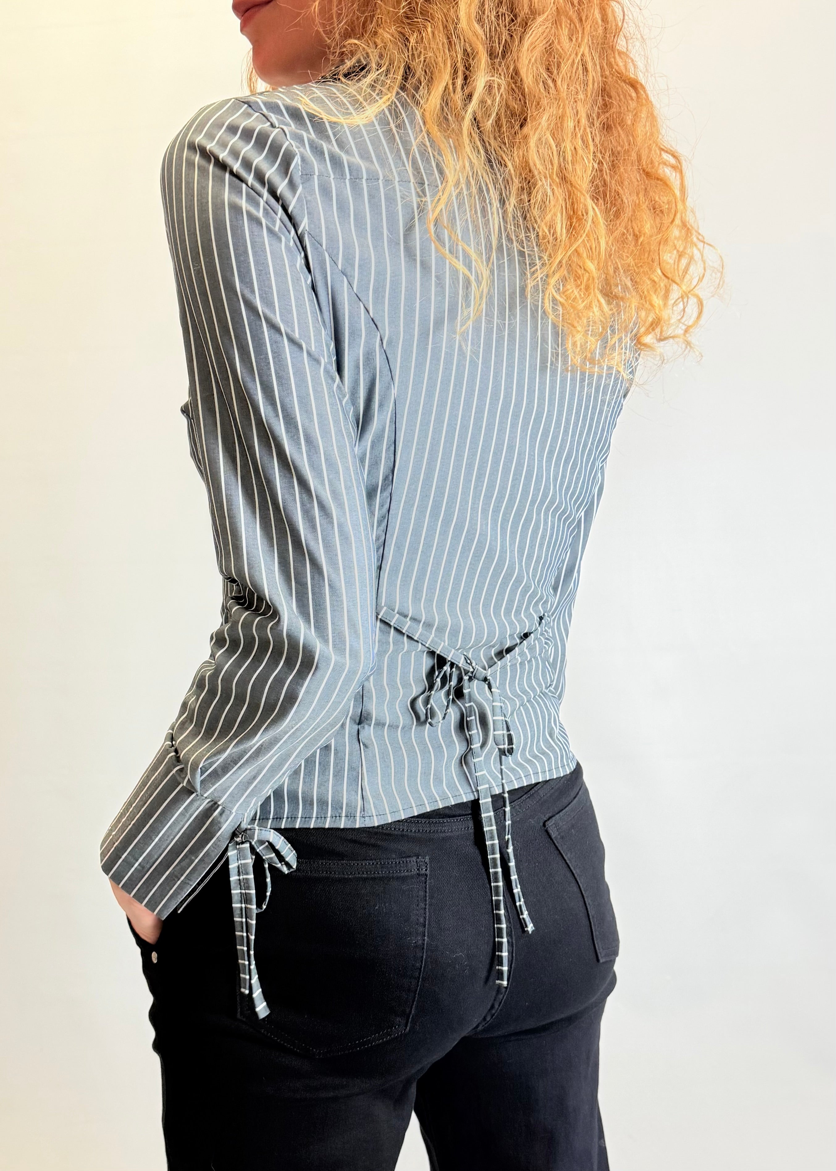 Person wearing a blue and white striped shirt with a drawstring waist, standing against a plain background.