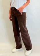 Person wearing brown wide-leg pants and white shoes on a plain background