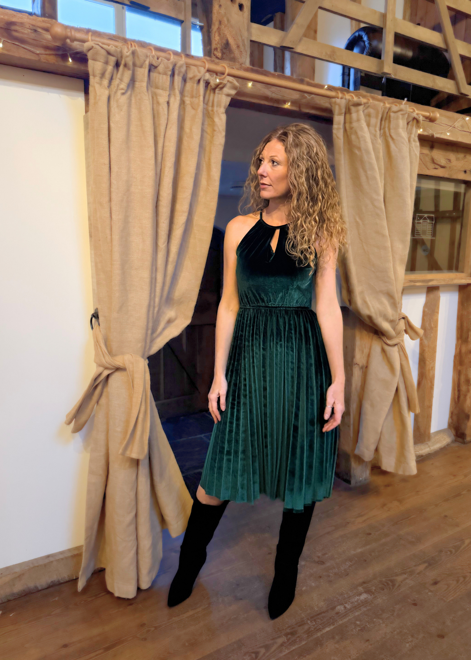 Lady wearing green velvet dress with long black boots.