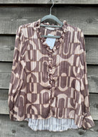 Patterned blouse on a hanger against a wooden background