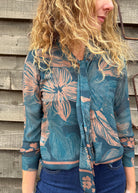 Person wearing a blue floral patterned shirt against a wooden wall.