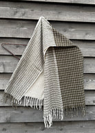 Woven blanket with fringes draped over a wooden surface