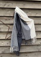 Textured blanket with fringes draped over a wooden surface