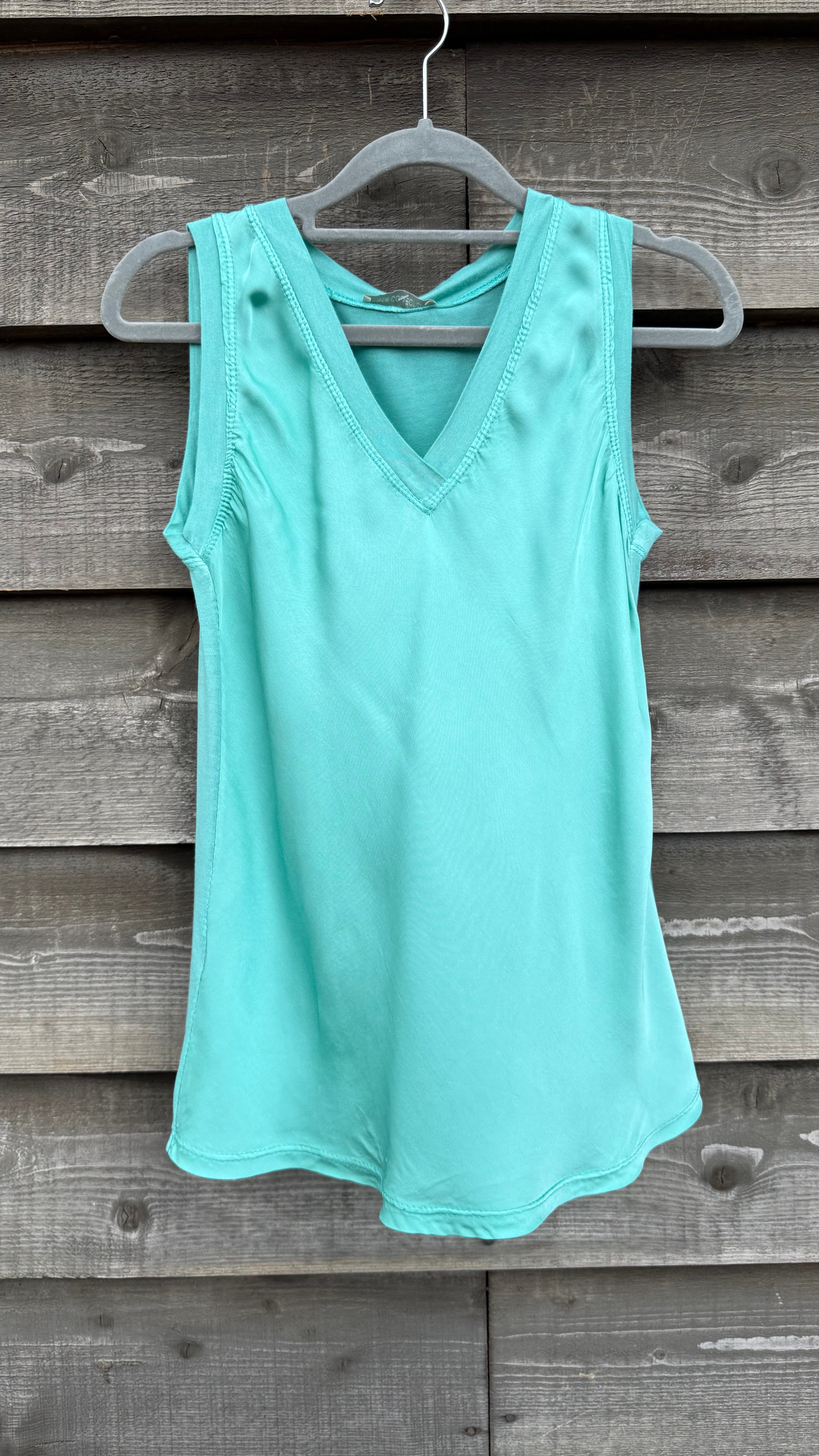 Mint green tank top on a hanger against a wooden background