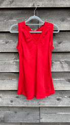 Red sleeveless top on a hanger against a wooden background